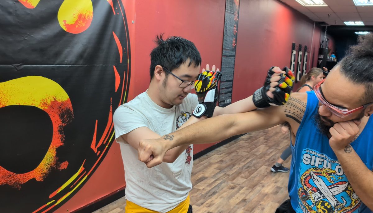 Student practicing a Wing Chun arm block against a partner's strike during kung fu class in Tampa