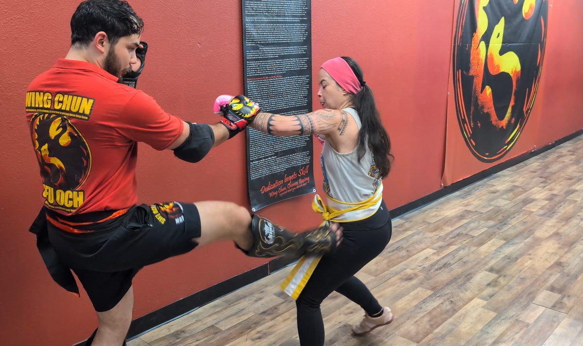 Student defending against a knee strike while punching in a Wing Chun sparring drill in Tampa