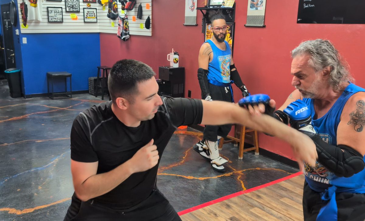 Two students sparring with gloves while another student watches during class at Tampa Wing Chun Kung Fu